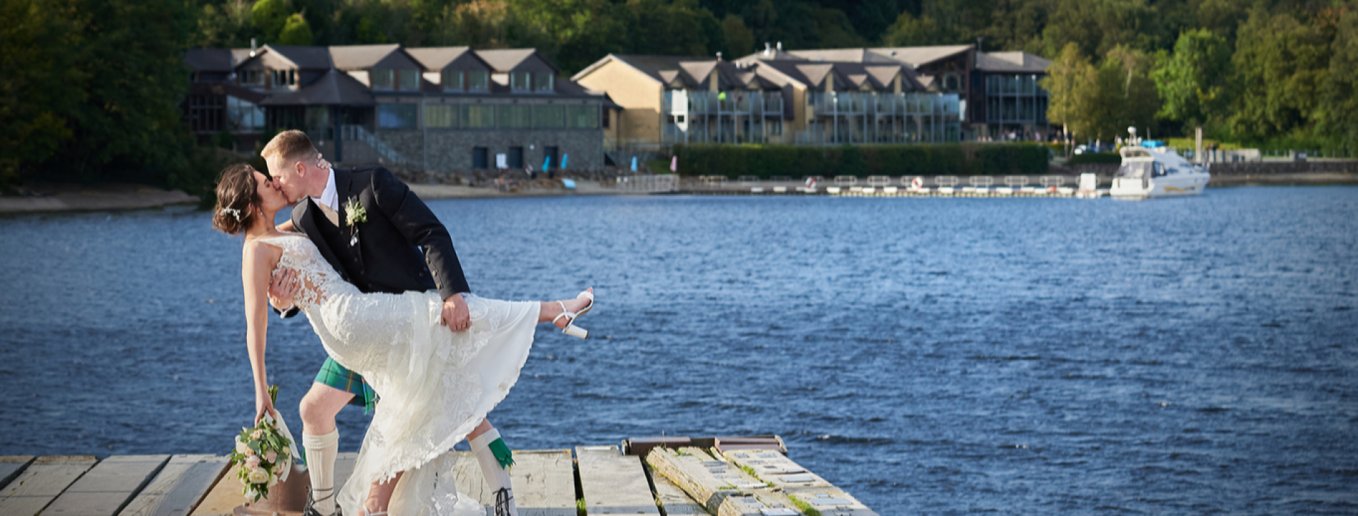 Bride and groom standing by the shore of Loch Lomond